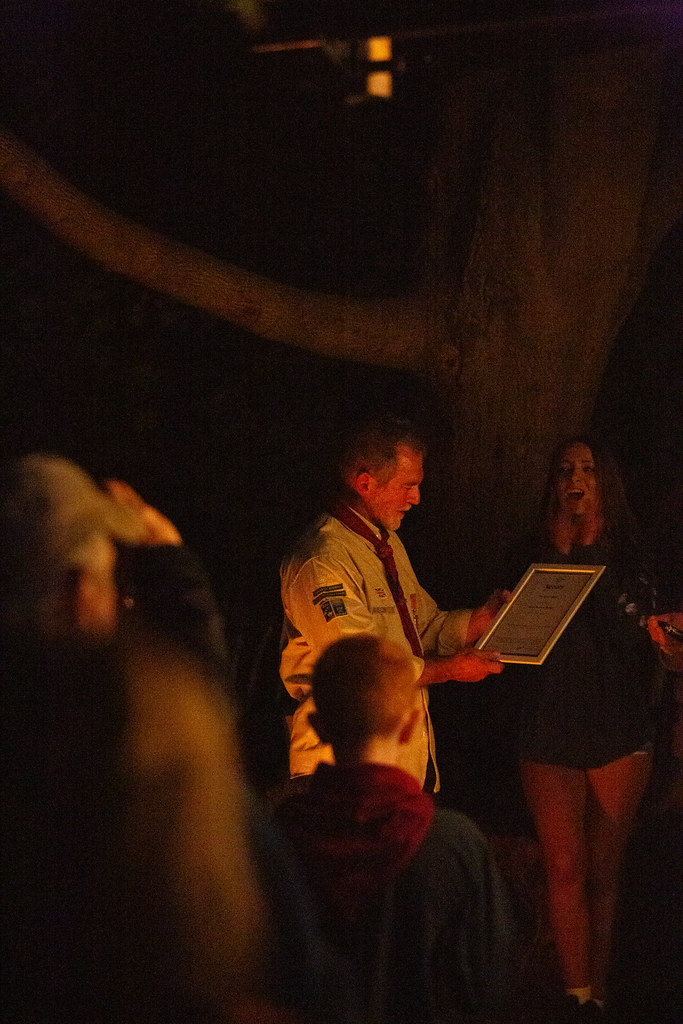 Keith reading his framed Silver Wolf certificate in front of assembled young people and adult volunteers.